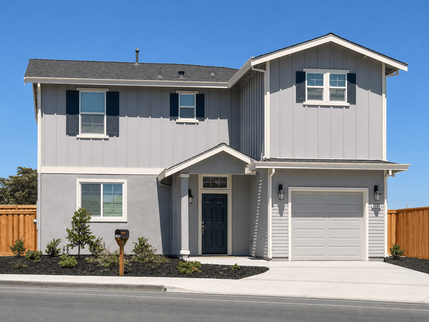 A modern house with a grey exterior and a black garage door.
